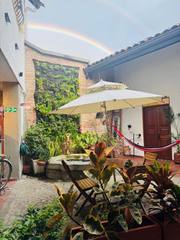 a patio with an umbrella and chairs and a fountain at HOTEL CASA BRESSE in Cali