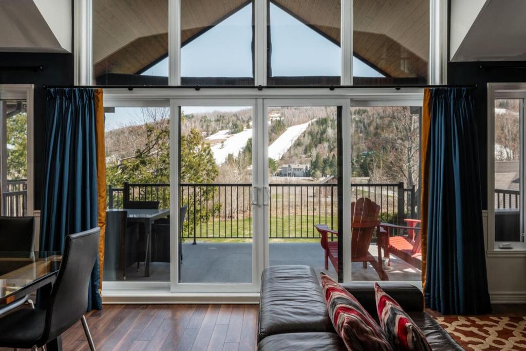 a living room with large windows and a couch at Spacious 3 bedroom condo Ski-in Ski-out St Sau in Saint-Sauveur-des-Monts