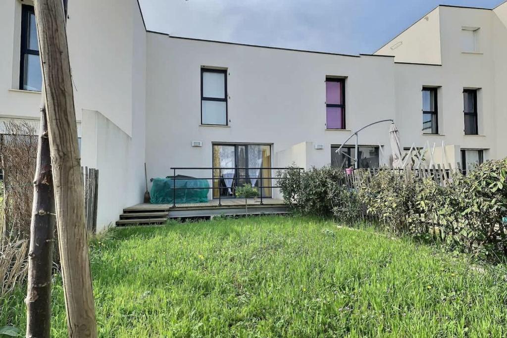 une maison blanche avec une cour herbeuse devant elle dans l'établissement Villa moderne avec 2 chambres dans une résidence à 500m de la plage, à Sérignan