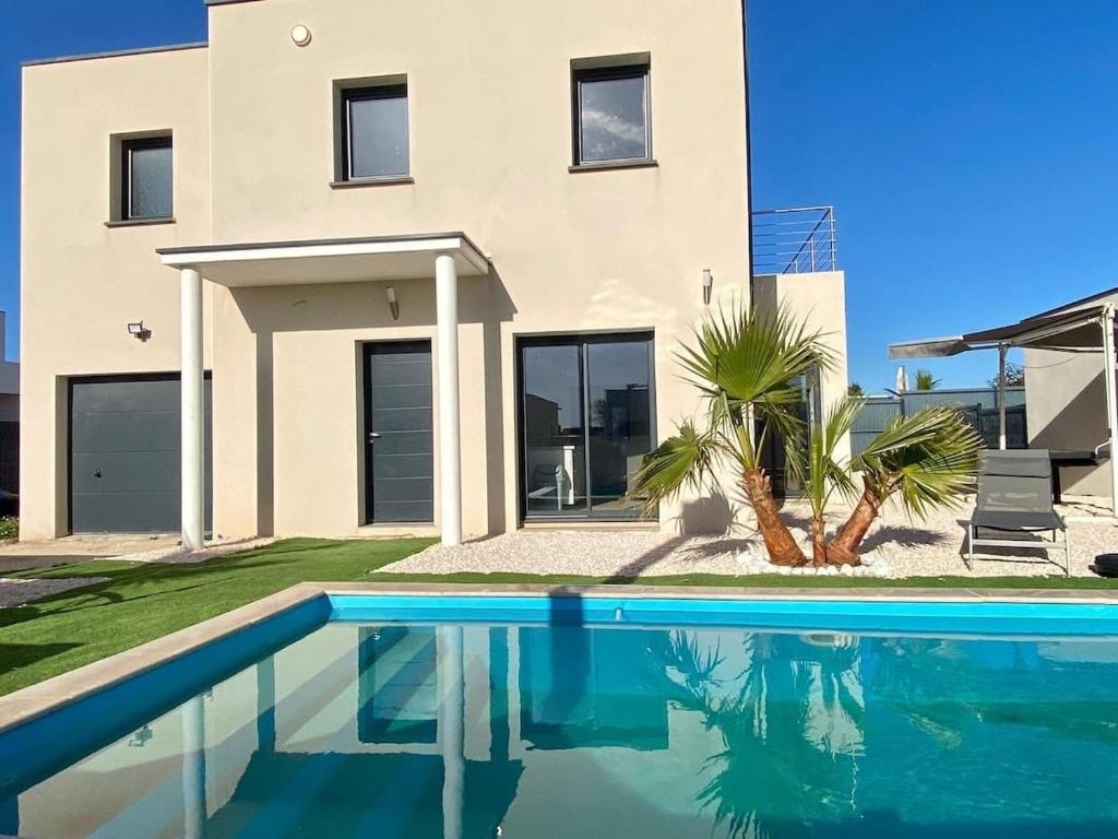 une maison avec une piscine devant une maison dans l'établissement Villa climatisée pour 8 personnes avec piscine privée, à Sérignan