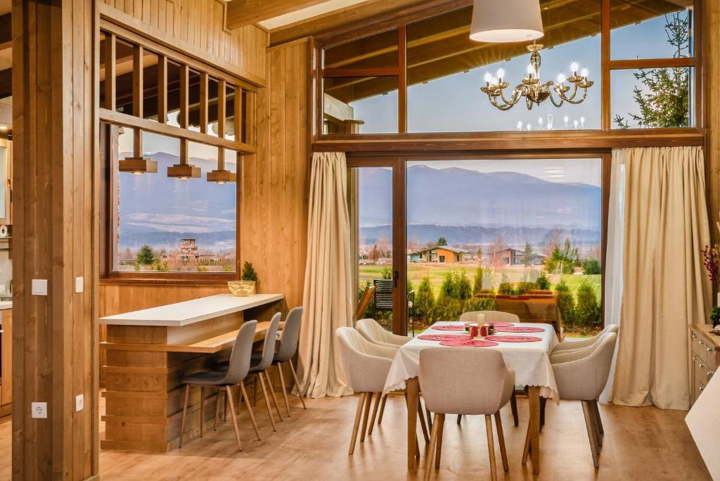 a dining room with a table and chairs and a large window at Pirin Golf Lux Villa for Ski & Chill in Bansko