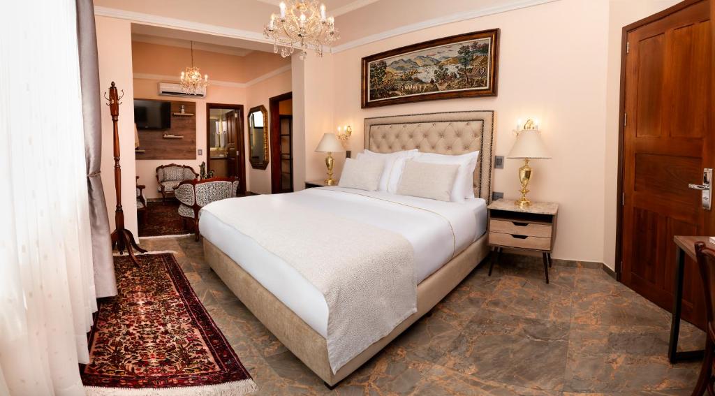 a bedroom with a large white bed with a chandelier at Hotel Boutique Patio Andaluz Cali Granada in Cali