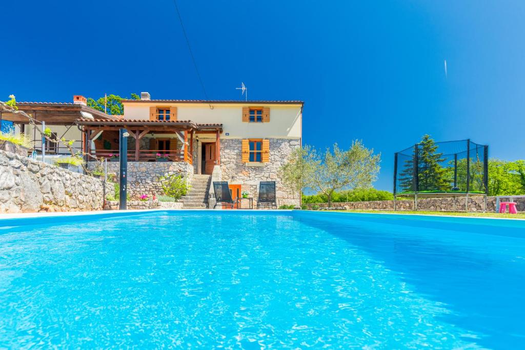a villa with a swimming pool in front of a house at Villa Dora - family house with saltwater pool in Gostinjac, Krk Island in Gostinjac