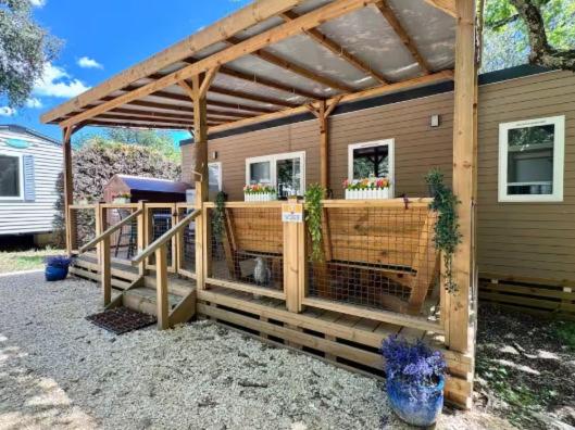 une pergola en bois sur le côté d'une maison dans l'établissement Ruoms Mobil-home camping animé près des Gorges, à Lagorce
