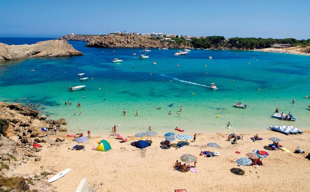 a beach with a bunch of people in the water at Costa Arenal 81 in Arenal d'en Castell