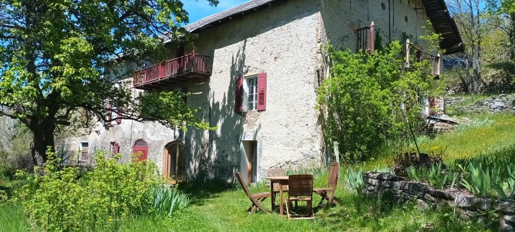 un vieux bâtiment avec une table et une chaise devant dans l'établissement Maison Authentique en Ubaye, à Jausiers