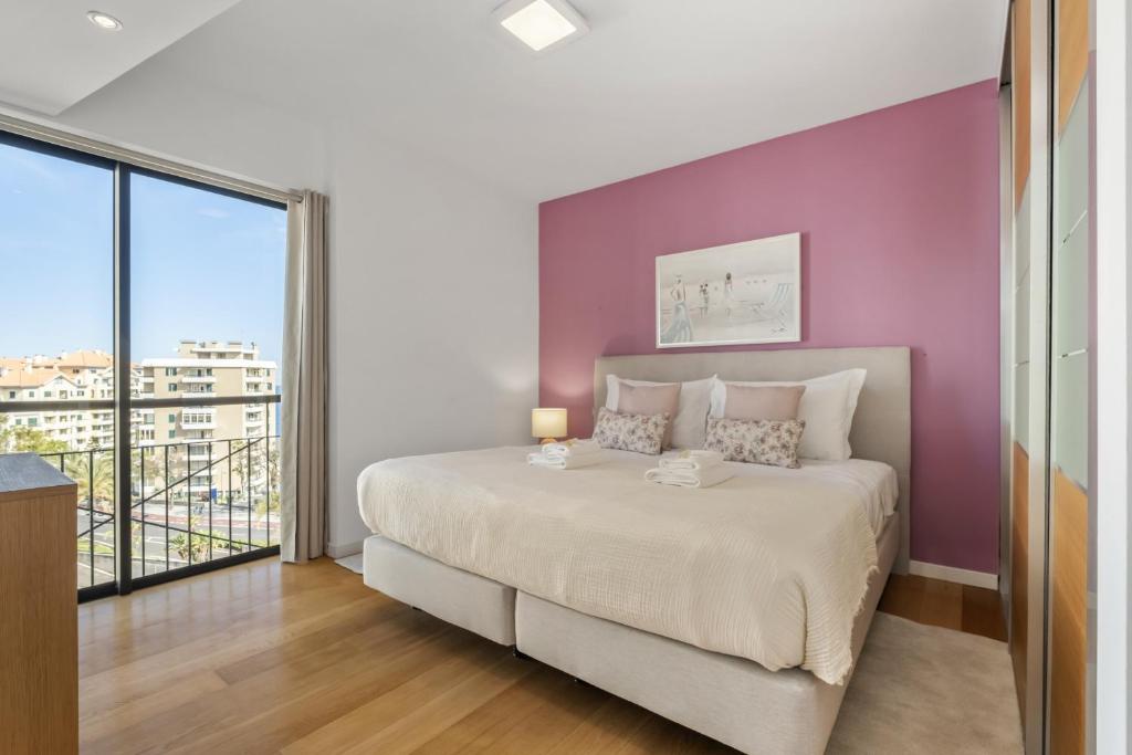 ein Schlafzimmer mit einem großen Bett mit einer lila Wand in der Unterkunft Forum Ocean View 5C by Homie in Ilhéu do Gorgulho