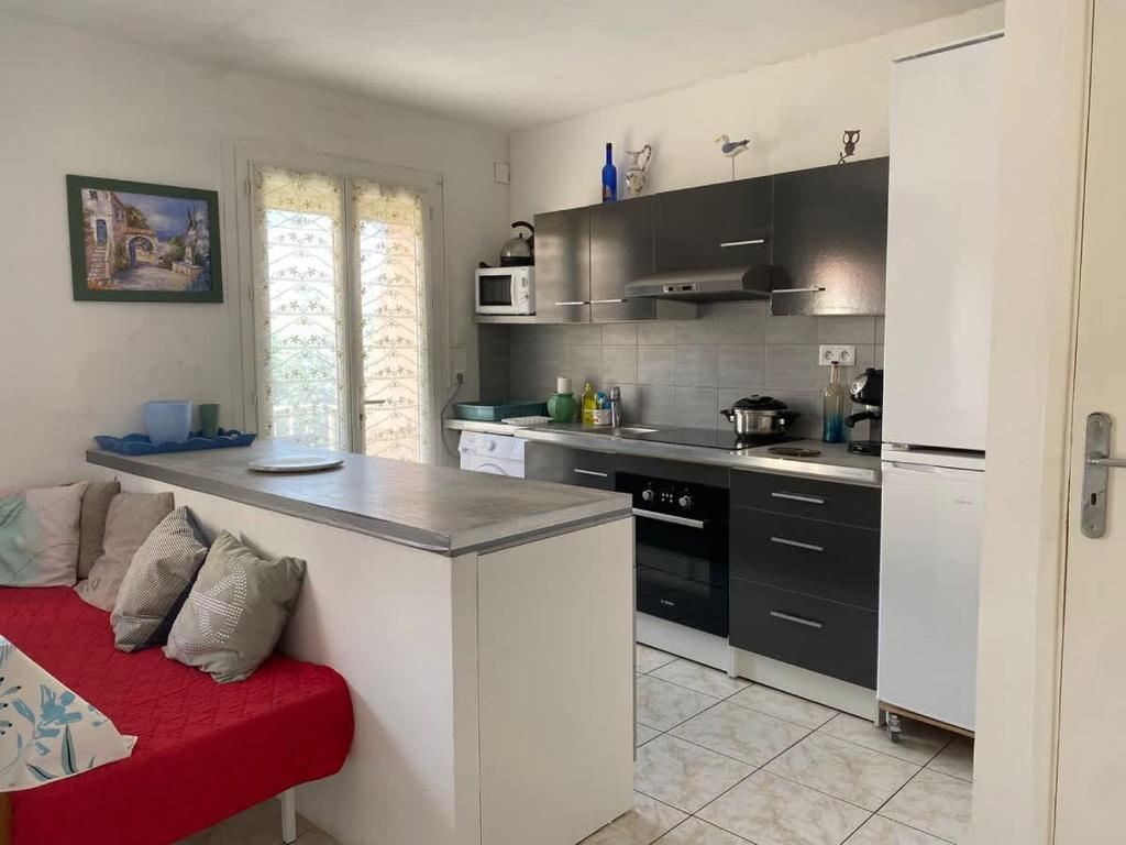 une cuisine avec un comptoir et un canapé rouge à l'intérieur dans l'établissement Appartement au centre-ville - Proche de la plage, à Valras-Plage