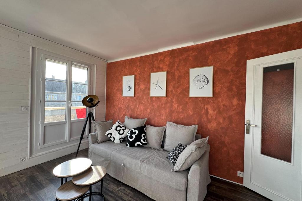 - un salon avec un canapé et un mur rouge dans l'établissement Family apartment near the castle of Caen, à Caen