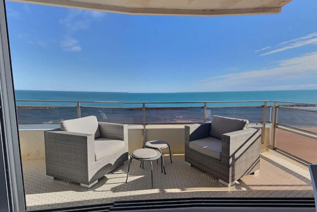 a balcony with two chairs and a table and the ocean at Magnifique appartement avec vue mer panoramique ! in Valras-Plage