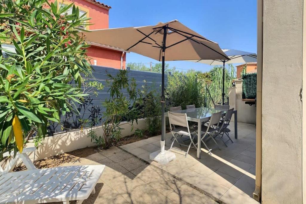 un patio avec un parasol, une table et des chaises dans l'établissement Agréable pavillon avec grande terrasse pour 6 personnes, à Valras-Plage
