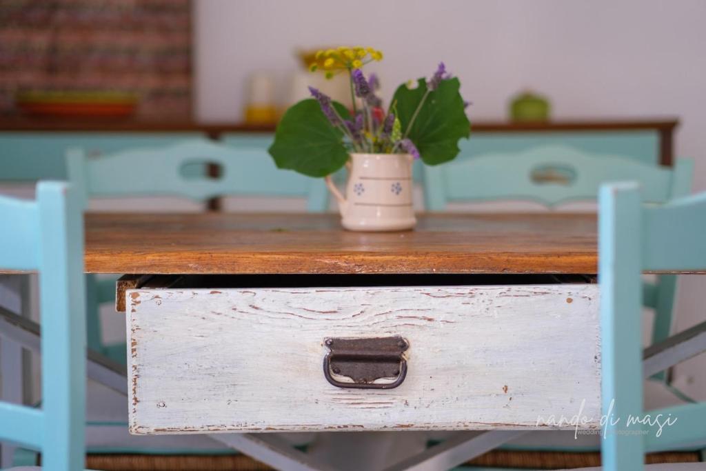 a wooden table with a pot of flowers on it at Masseria Giangrande - Rooms and Apartment in Polignano a Mare