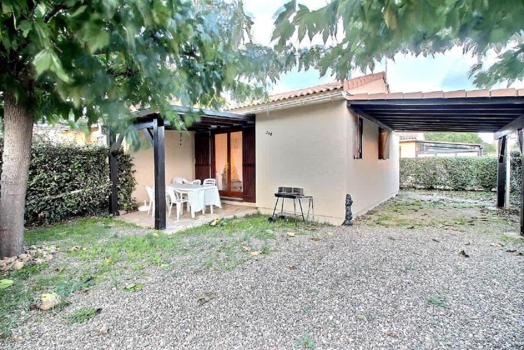 une maison avec une table et des chaises dans une cour dans l'établissement Pavillon indépendant pour 6 personnes dans une résidence sécurisée avec piscine, à Valras-Plage