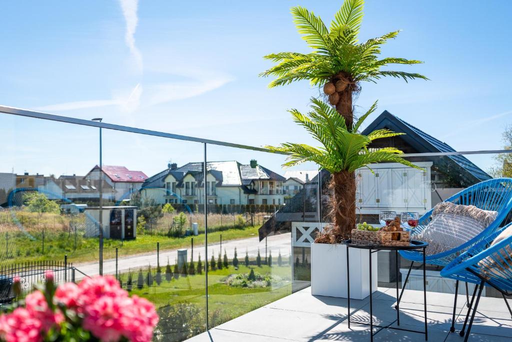a balcony with palm trees and a table and chairs at Apartamenty Bellamaya - Kapitanska 8 in Grzybowo