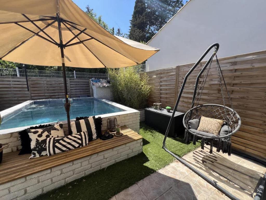 - une piscine avec un parasol, une chaise et une balançoire dans l'établissement Valras-Loc Villa Dolce Vita, à Béziers