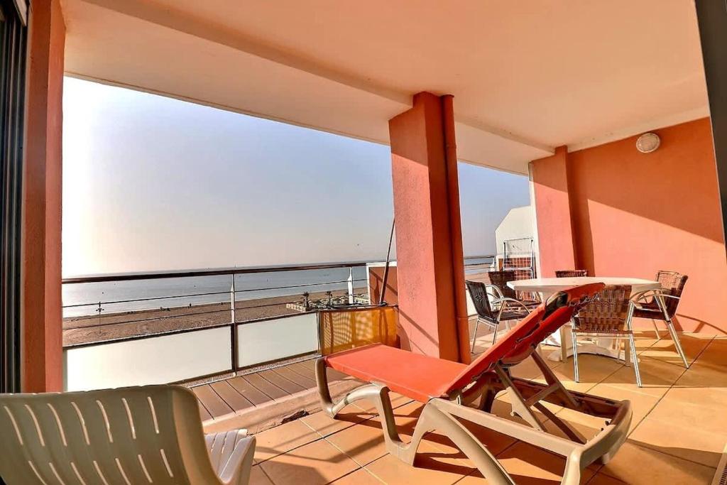 un balcon avec une table et des chaises et une grande fenêtre dans l'établissement Magnifique appartement en front de mer, à Valras-Plage
