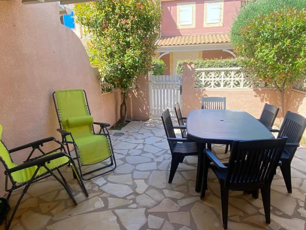 un patio avec une table et des chaises sur un patio dans l'établissement LES JARDINS DE LA MER -Coquet pavillon à deux pas de la plage, à Valras-Plage