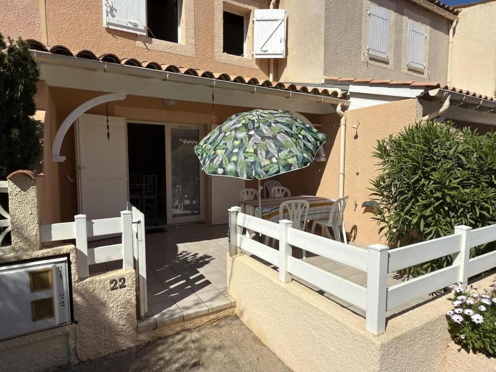 une terrasse avec une table et un parasol sur une maison dans l'établissement A 200m de la plage Confortable pavillon pour 6 personnes, à Valras-Plage