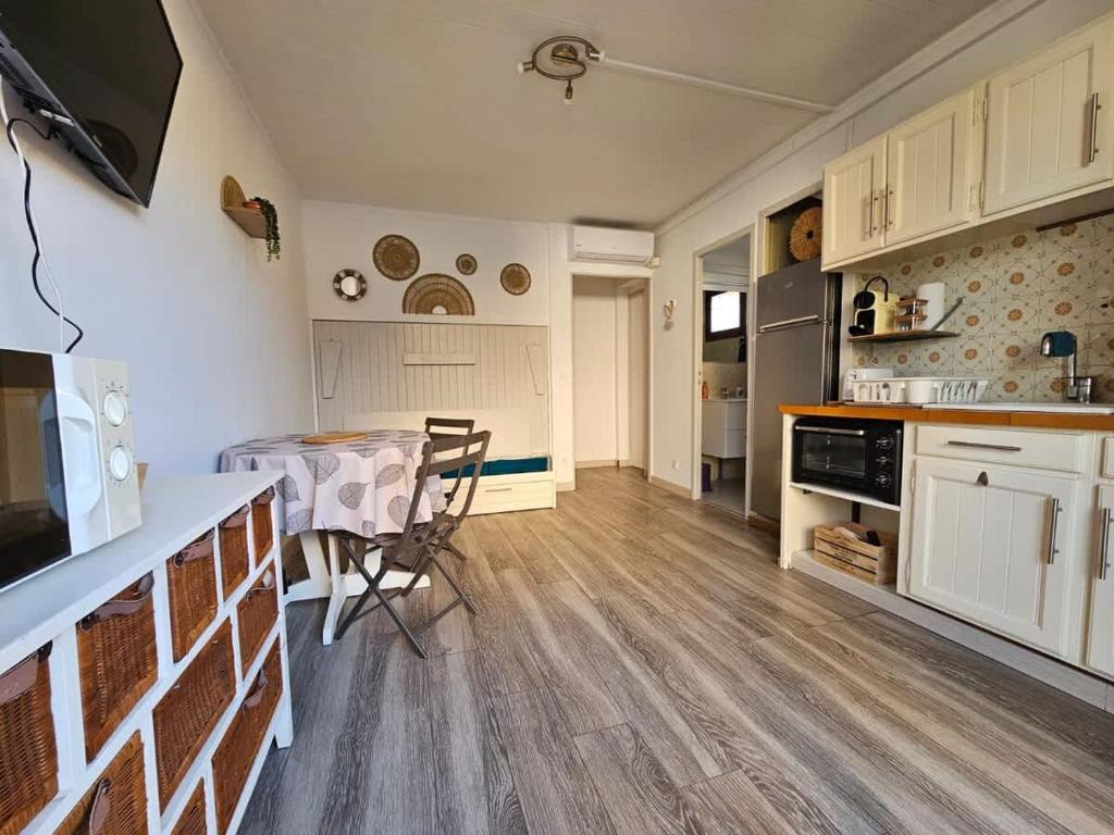 une cuisine et une salle à manger avec une table et des chaises dans l'établissement Valras-Loc - Studio avec terrasse et exterieur, à Valras-Plage