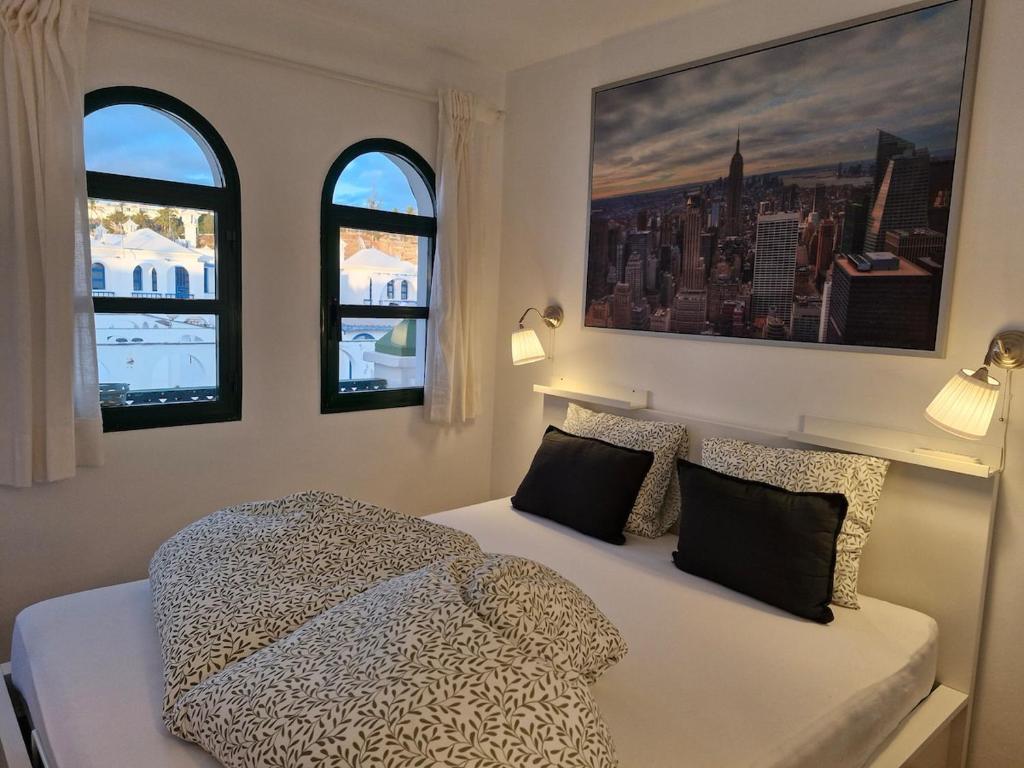 a bedroom with a bed and two windows at Bungalow Faro y Dunas Maspalomas in Maspalomas