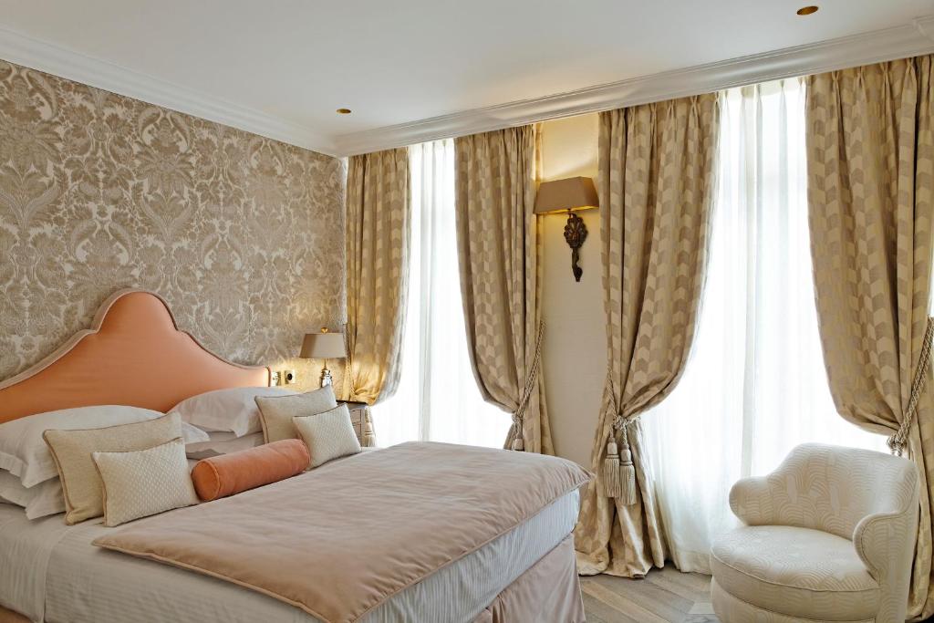 a bedroom with a bed and a chair and windows at Relais Christine in Paris