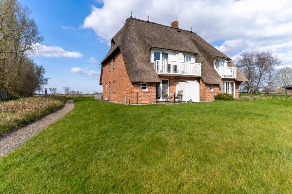 une maison ancienne avec un toit de chaume sur un champ dans l'établissement Auszeit unter Reet, à Böhl