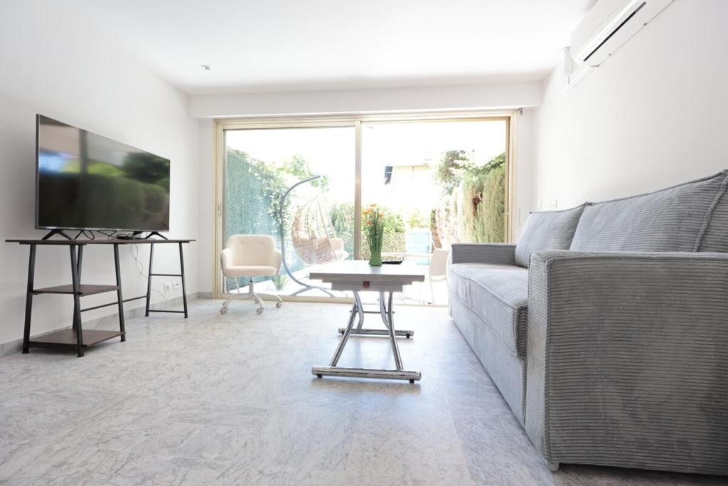 un salon avec un canapé et une télévision dans l'établissement Roses des Mers - Apt Standing 2 Prs - Clim - Parking, à Antibes
