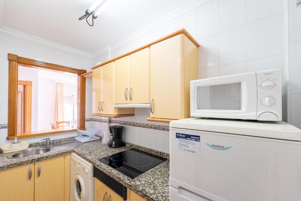 a kitchen with a white refrigerator and a microwave at Apartamentos Solset Nerja in Nerja