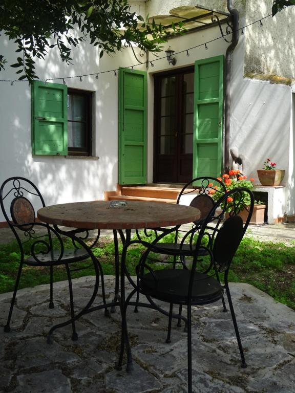 a table and chairs in front of a house with green shutters at Camera D'Ambra in Campiglia Marittima