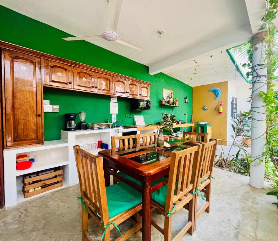 a kitchen with green walls and a wooden table and chairs at Palmar la Punta 5 Starlink 2min walk to the beach in Brisas de Zicatela