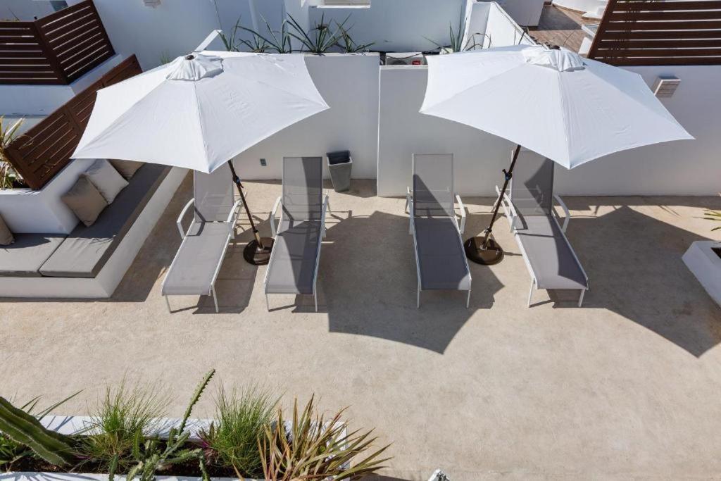 two white umbrellas and chairs in a courtyard at central and quiet apartment playa in Playa del Carmen