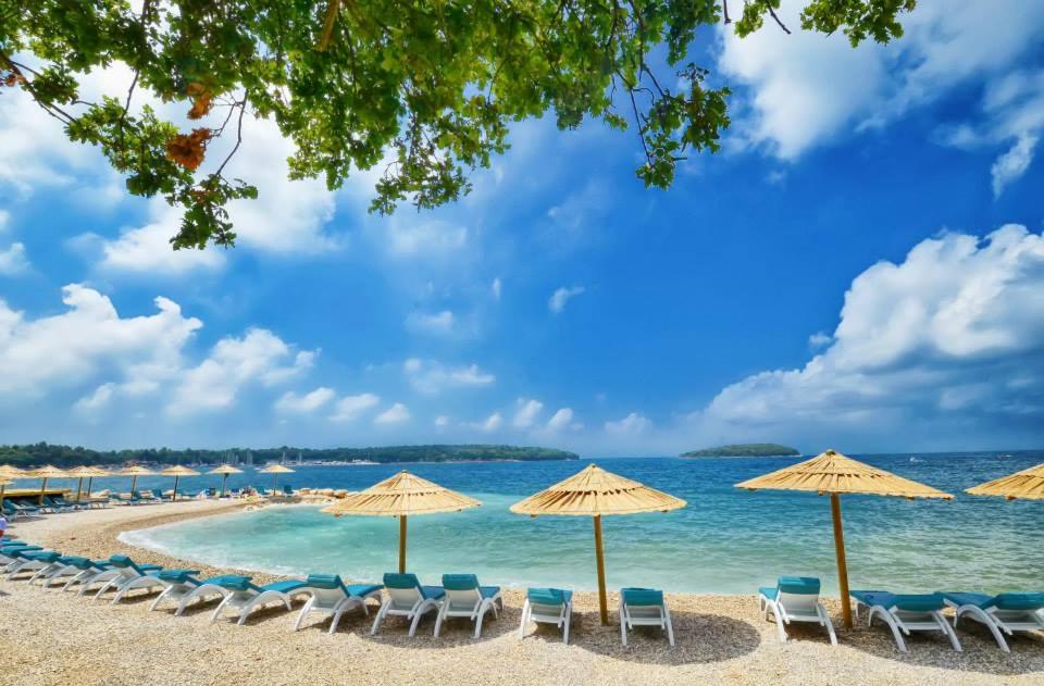 a beach with chairs and umbrellas and the ocean at Apartment Vita in Funtana