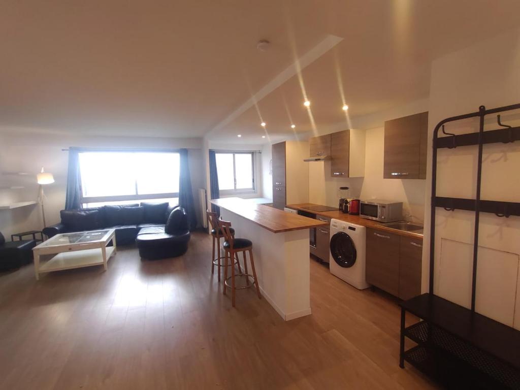un salon avec un canapé et une cuisine avec un comptoir dans l'établissement 4 bedrooms, La Défense, 5 min walk to metro, à Courbevoie