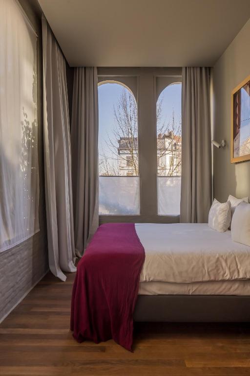een slaapkamer met een groot bed en 2 ramen bij Hotel Pilar in Antwerpen