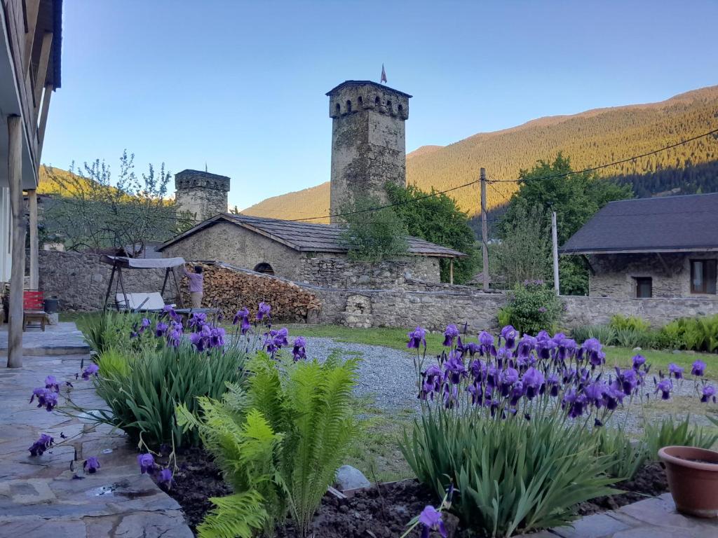 a garden with purple flowers in front of a building at Bapsha Guesthouse in Mestia