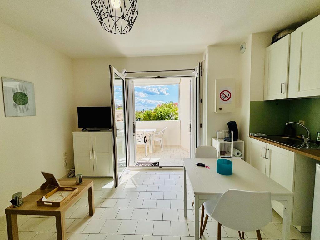 une cuisine avec une table et une vue sur un patio dans l'établissement 5 min de la Mer à pieds,Plage Richelieu,Le Cap d Agde,pour 2ou 4pers, au Cap d'Agde