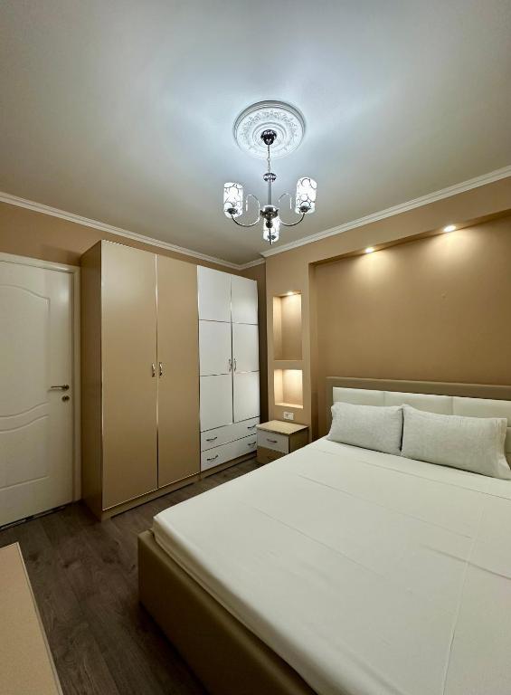 a bedroom with a large white bed and a chandelier at Korca Apartment in Korçë