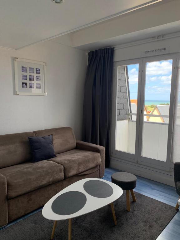 un salon avec un canapé et une table dans l'établissement Blue, studio avec vue mer et matelas en mezzanine, à Courseulles-sur-Mer