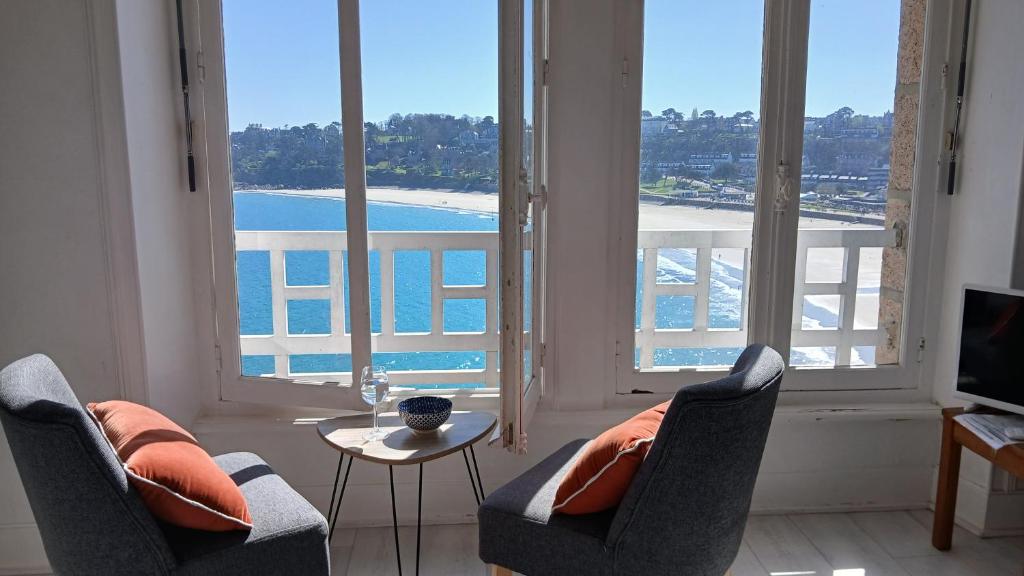 - un salon avec deux chaises et une vue sur l'océan dans l'établissement Splendide vue mer studio, à Perros-Guirec