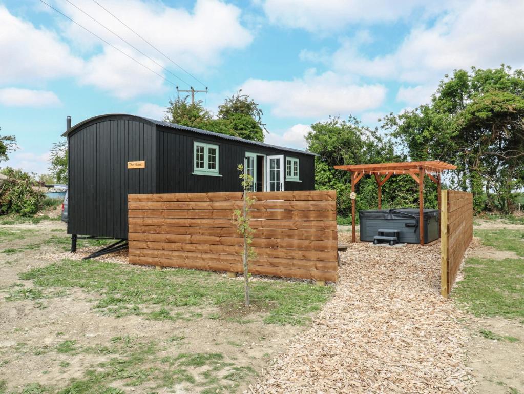 a black tiny house with a wooden fence at The Heron in Cambridge