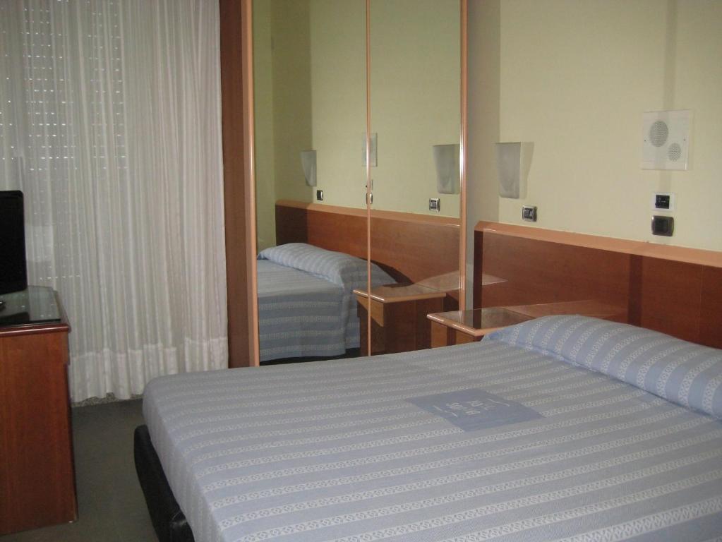 Habitación de hotel con cama y espejo en Hotel Soraya, en San Benedetto del Tronto