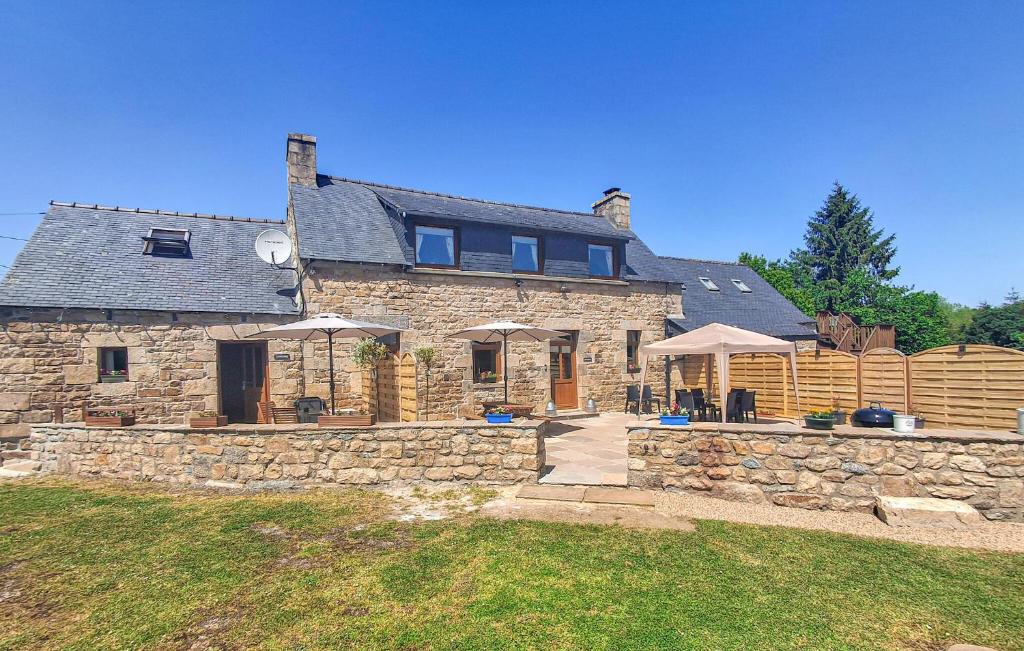 une grande maison en pierre avec un mur en pierre dans l'établissement Ravissante Maison Bretonne, à Louargat