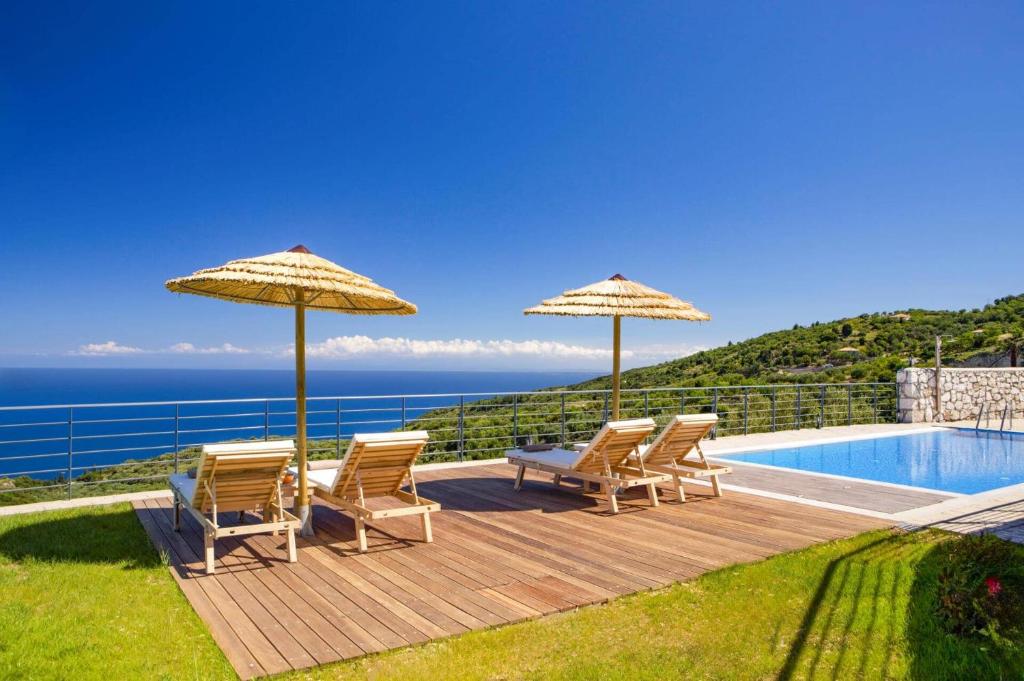 a deck with chairs and umbrellas next to a swimming pool at Villa Drimonas Erato by Villa Plus in Drymon
