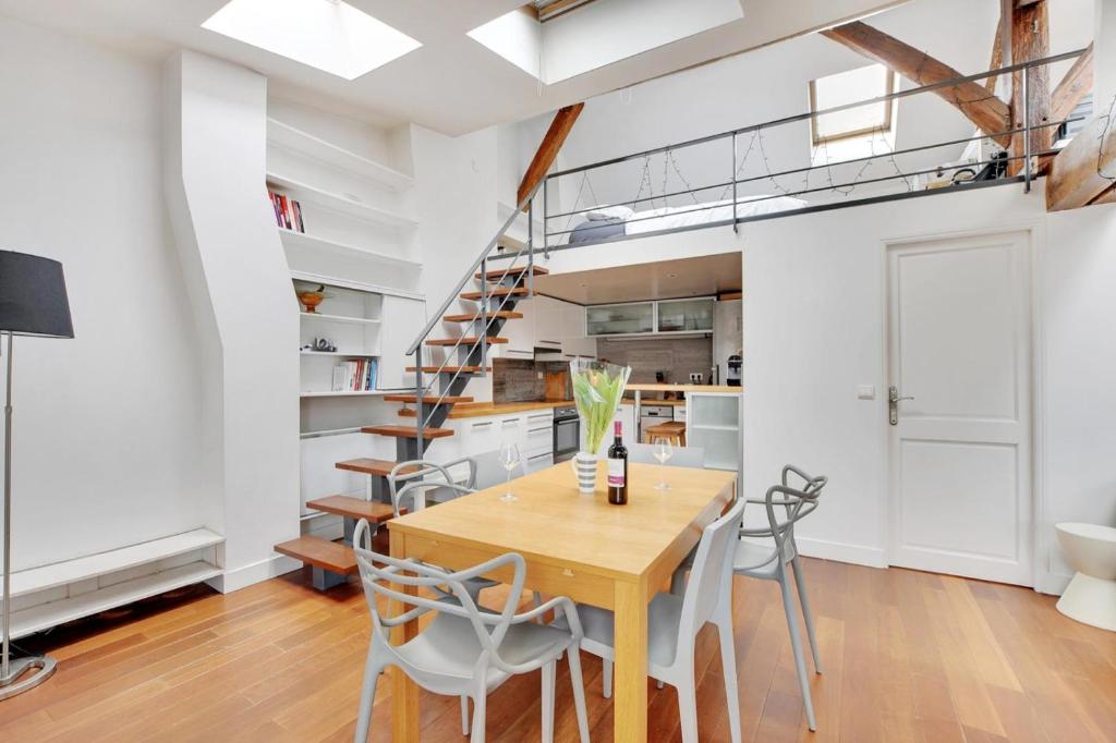 une cuisine et une salle à manger avec une table et des chaises en bois dans l'établissement Cosy Duplex City Center, à Paris