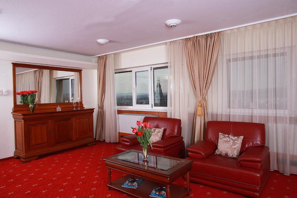 una sala de estar con 2 sillas rojas y una mesa. en Hotel Moldova, en Iaşi