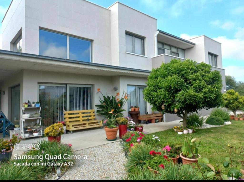 a white house with a garden in front of it at Habitación en casa moderna con jardín in Santa Cruz de Bezana