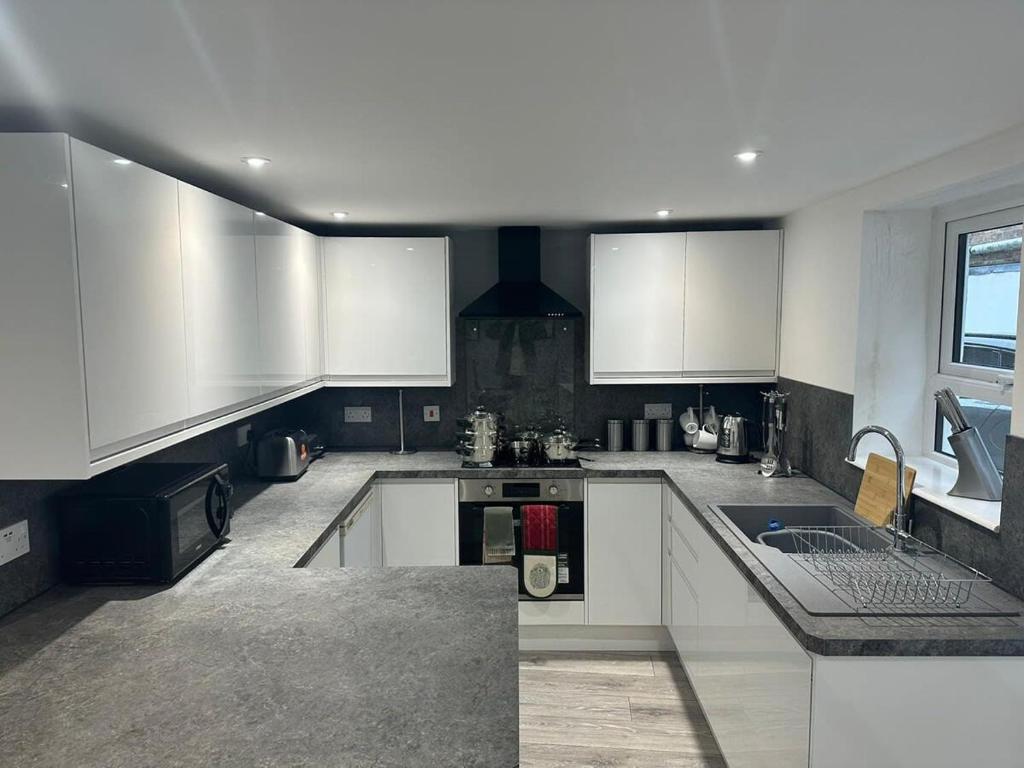 a large kitchen with white cabinets and a sink at The Lucia Apartments II - 1 Bedroom Town Centre Apartment - Contractor Friendly - Free Parking - Full Kitchen - Washer Dryer - Spacious - Ideal for Work Stays in Huntingdon