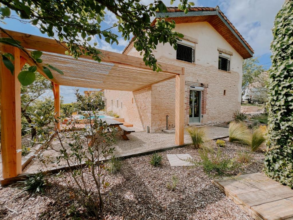 an external view of a house with a wooden pergola at La Maison Des Pierres Blondes in Orban