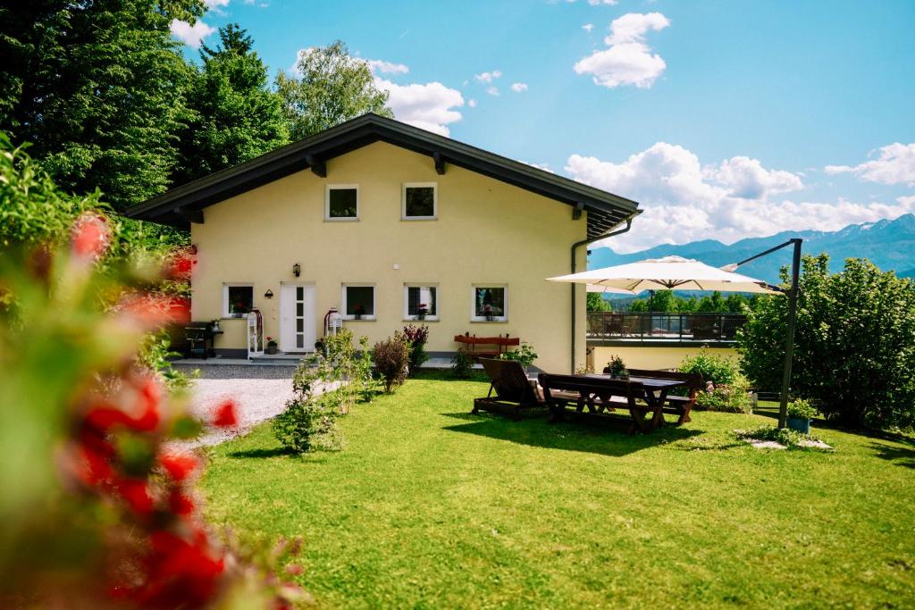a house with a picnic table and an umbrella at Schwalbennest Velden in Velden am Wörthersee