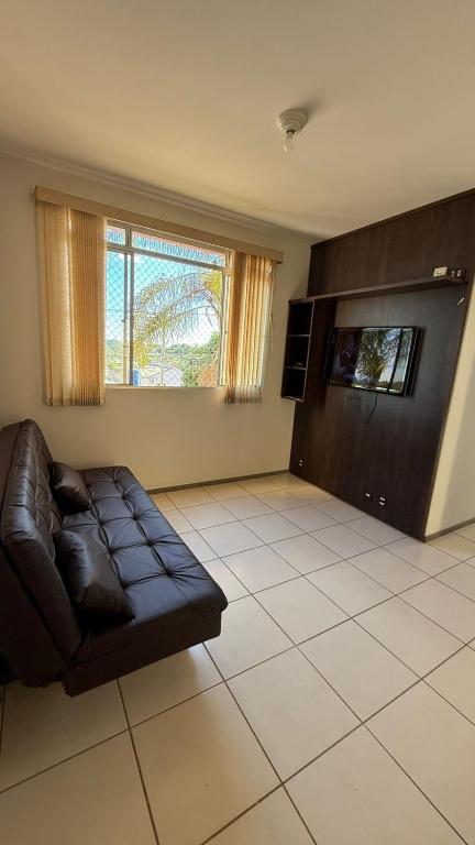 a living room with a leather couch and a window at Excelente e amplo Apto 2 Q in Araguari